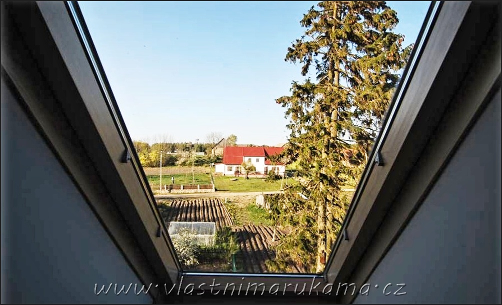 Výhled ze střešního okna na zeleninovou zahrádku a stromy